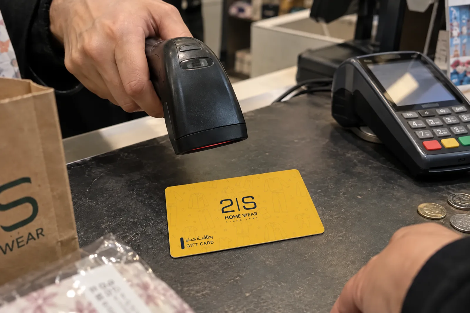 A cashier scanning a printed gift card at the till
